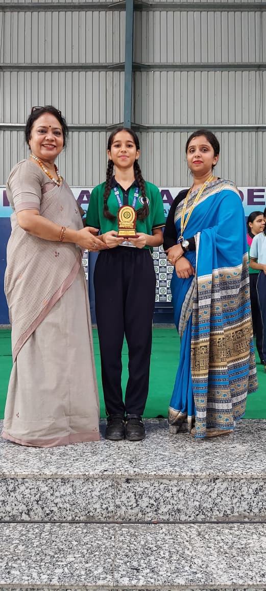 विद्यालय नेतृत्व के साथ ट्रॉफी थामे विद्यार्थी उपलब्धिकर्ता